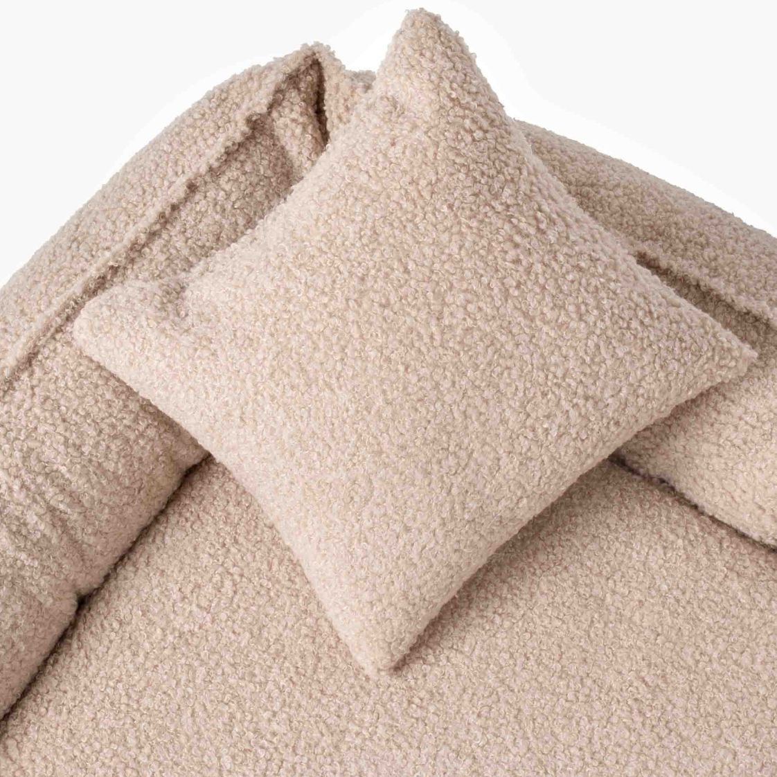 Närbild på mjukt beige bouclétyg och välfyllda kanter i hundbädden ROYAL